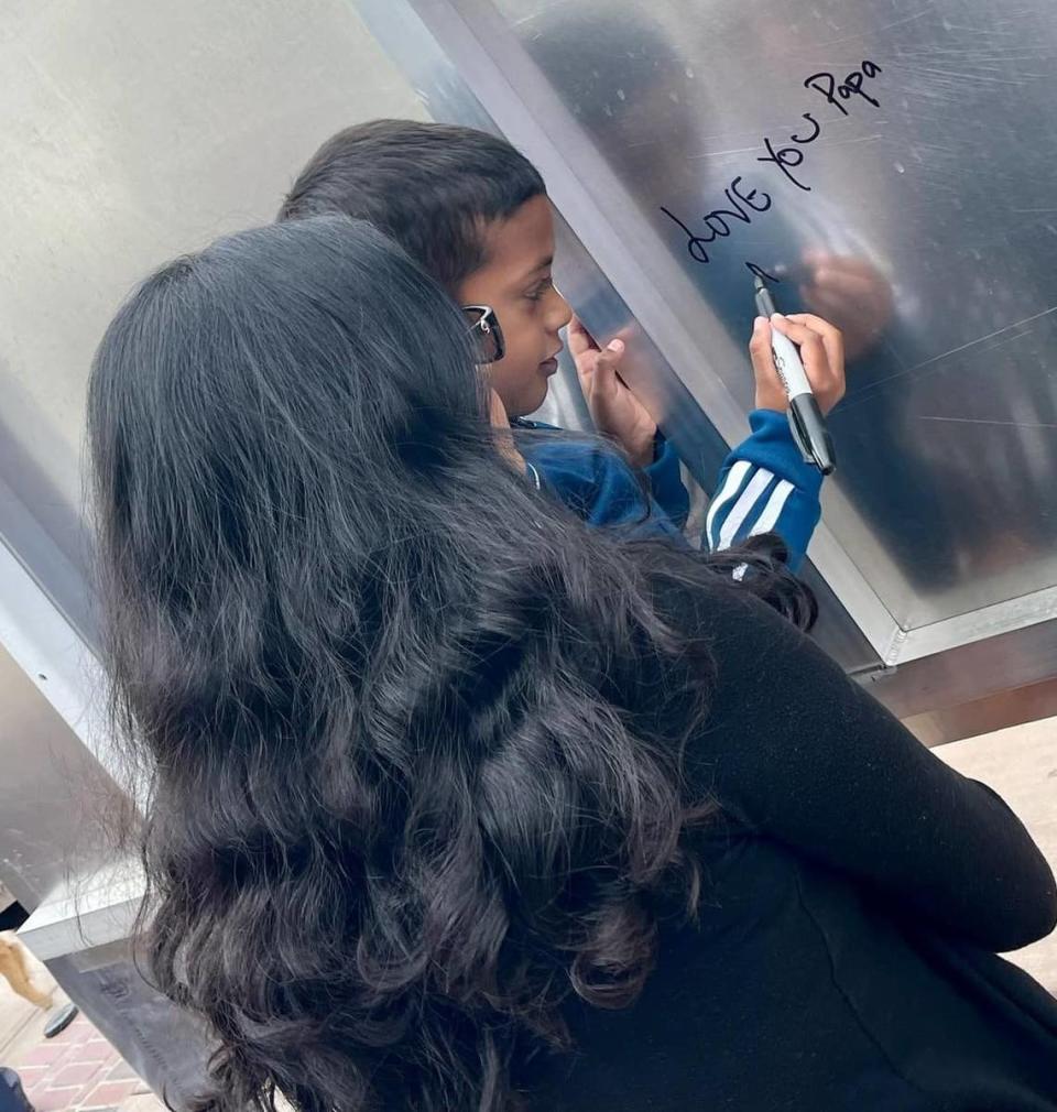 Arnav Singh writes a message to his father on the back of the sign that names a portion of Highway 33 in Newman as the “Corporal Ronil Singh Memorial Highway.”