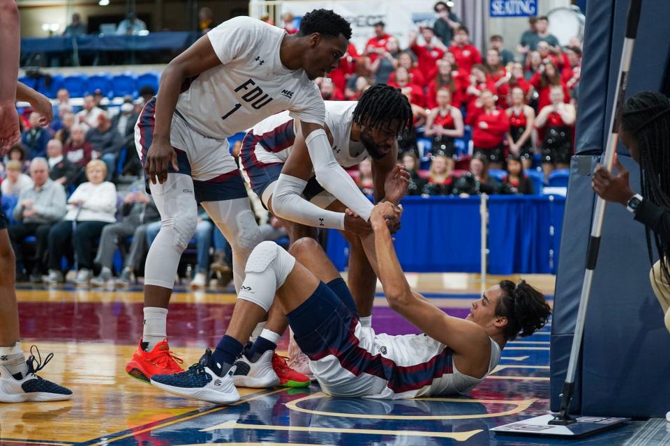 FDU's Joe Munden Jr. and Ansley Almonor help a teammate up in the NEC Tournament semifinals at the Rothman Center