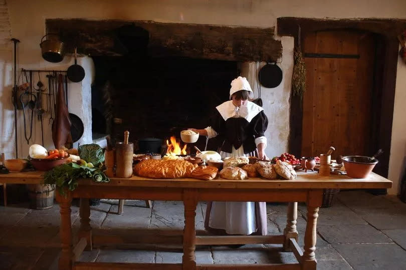 A woman stands by a table inside Llancaiach Fawr manor house