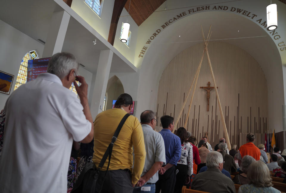 Parishioners stand to receive communion during the rededication ceremony and Sunday Mass at Sacred Heart Church of the First Peoples on July 17, 2022, in Edmonton, Alberta. In 2020, the church was damaged in a large fire and has now been renovated ahead of Pope Francis' visit to the Canadian province. (AP Photo/Jessie Wardarski)