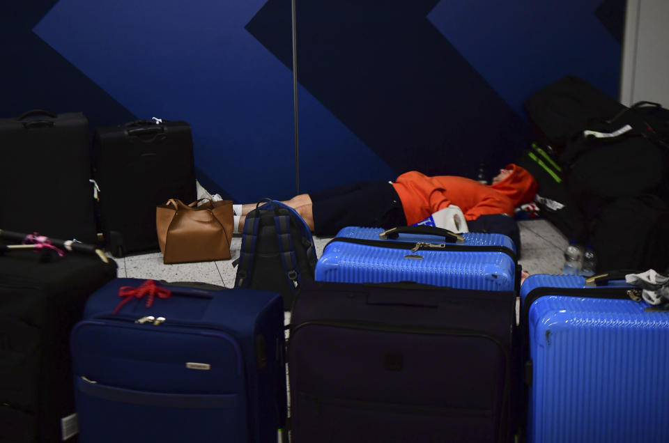 A passenger sleeps surrounded by suitcases at Gatwick airport, as the airport remains closed after drones were spotted over the airfield last night and this morning, in Gatwick, England, Thursday, Dec. 20, 2018. Drones spotted over the runway forced the shutdown of London's Gatwick Airport on Thursday during one of the busiest times of the year, stranding or delaying tens of thousands of Christmas-season travelers and setting off a hunt for the operator of the intruding aircraft. (Victoria Jones/PA via AP)