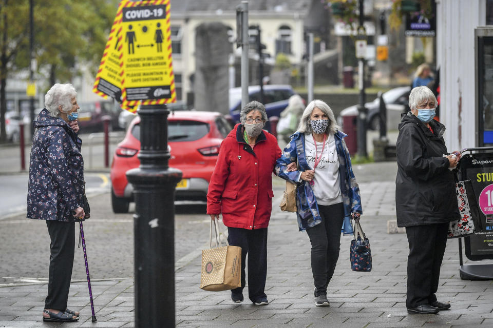 Shoppers queue for food in Caerphilly centre, as the county borough is to be placed under a local lockdown following a "significant rise" in coronavirus cases, in Caerphilly, South Wales, Tuesday, Sept. 8, 2020. On Tuesday evening, a local lockdown comes into force in the Welsh district of Caerphilly following a spike in cases. Under the new restrictions, people will not be allowed to enter or leave the area without a reasonable excuse. Everyone over the age of 11 will also be required to wear face coverings in shops — the first time this will be mandatory in Wales. Meetings with other people indoors and extended households will not be allowed, while overnight stays have also been banned. (Ben Birchall/PA via AP)