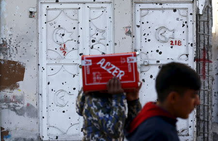 Men walk past a bullet-riddled house in the southeastern town of Silvan in Diyarbakir province, Turkey, December 7, 2015. REUTERS/Murad Sezer