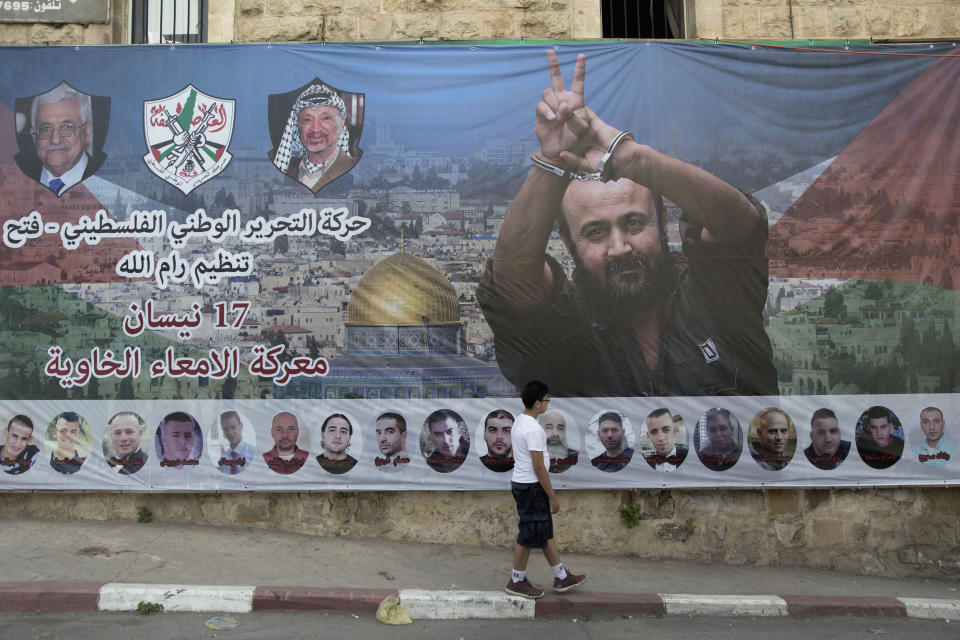 FILE - A banner with a picture of jailed Palestinian uprising leader Marwan Barghouti and some fellow inmates, with Arabic that reads "Palestinian National Liberation Movement, Ramallah organization, Fatah, April 17th, the battle of the empty intestines," hang on a building, in the West Bank city of Ramallah, Monday, May 1, 2017. Hamas officials say that any cease-fire deal with Israel should include the release of prisoner Marwan Barghouti — a leader of the militant group's main political rival. The demand by Hamas marks the central role Barghouti plays in Palestinian politics — even after more than two decades behind bars and sentenced by Israel to multiple life terms in prison. (AP Photo/Nasser Nasser, File)