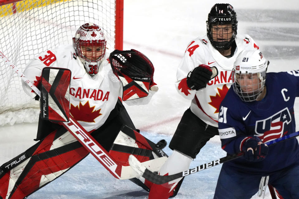 United States Hilary Knight (21) tries to redirect the puck in front of Canada defender Renata Fast (14) and Canada goaltender Emerance Maschmeyer (38) during the third period of a rivalry series women's hockey game Wednesday, Nov. 8, 2023, in Tempe, Ariz. (AP Photo/Ross D. Franklin)