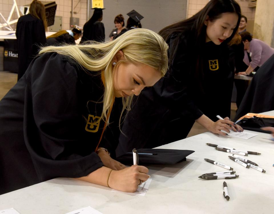 Sara Berrymon of St. Louis signs her name on a pronunciation card on Friday at Mizzou Arena before graduating with an elementary education degree from the University of Missouri College of Education and Human Development.