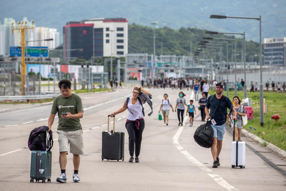 Travelers walk with their luggage along a road towards the Hong Kong International Airport during a protest in Hong Kong, China, on Sunday, Sept. 1, 2019. | Paul Yeung/Bloomberg via Getty Images