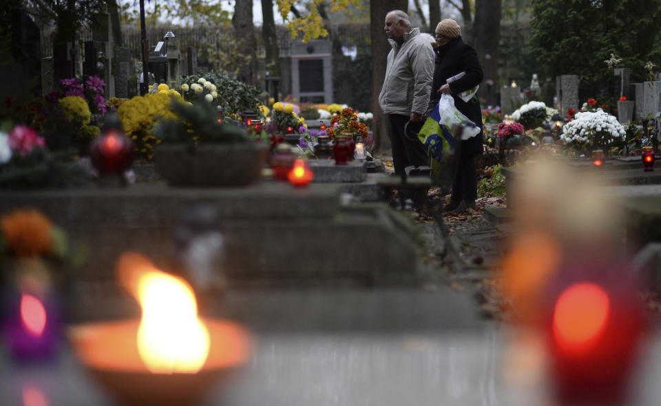 <p>People stop in front of a grave at the Powazki cemetery in Warsaw, Poland, Wednesday, Nov. 1, 2017. Candles and flowers cover tombstones in graveyards across Poland on All Saints’ Day, as people honor the saints and their departed friends and family, in Christian tradition. (Photo: Alik Keplicz/AP) </p>