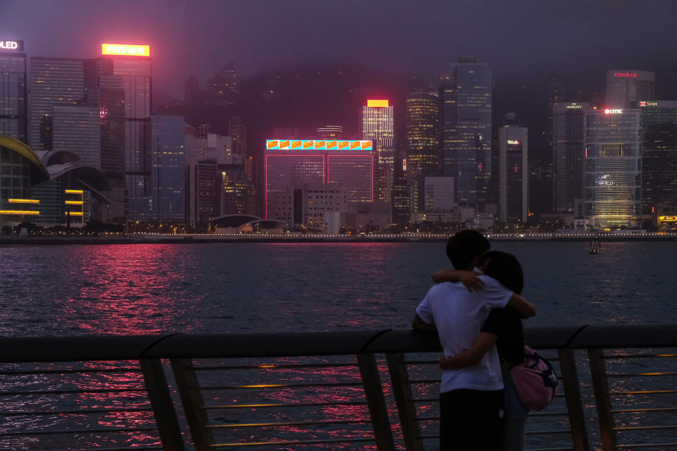 A couple across from illuminated skyscrapers on Victoria Harbor in Hong Kong on May 28, 2020. | Roy Liu—Bloomberg/Getty Images.