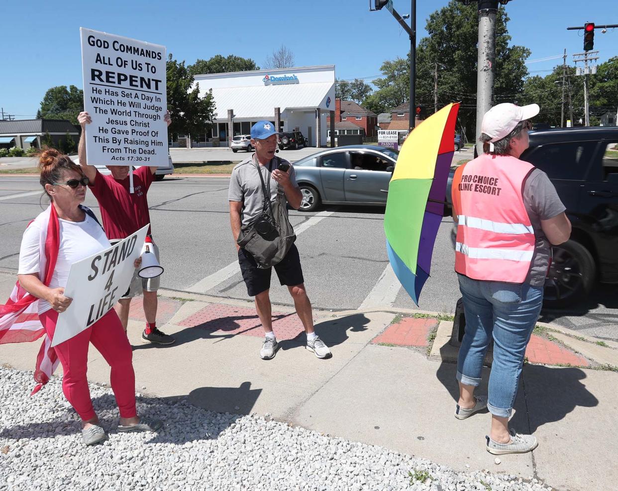 An abortion-rights clinic escort, right, prepares to shield an incoming patient into the clinic from potential harassment of anti-abortion protesters at the Northeast Ohio Women's Center in Cuyahoga Falls on Monday.