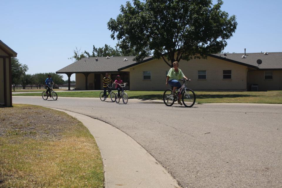 Several children and an adult ride bikes through the Buckner Children and Family Services campus on Brentwood Avenue.