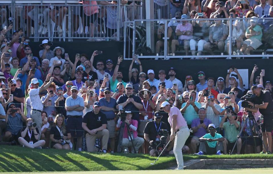Fans look on as Rory McIlroy chips his ball onto the 18th green during the final round of the Wells Fargo Championship at Quail Hollow Club in Charlotte, NC on Sunday, May 12, 2024. McIlroy won the Wells Fargo Championship at -17.