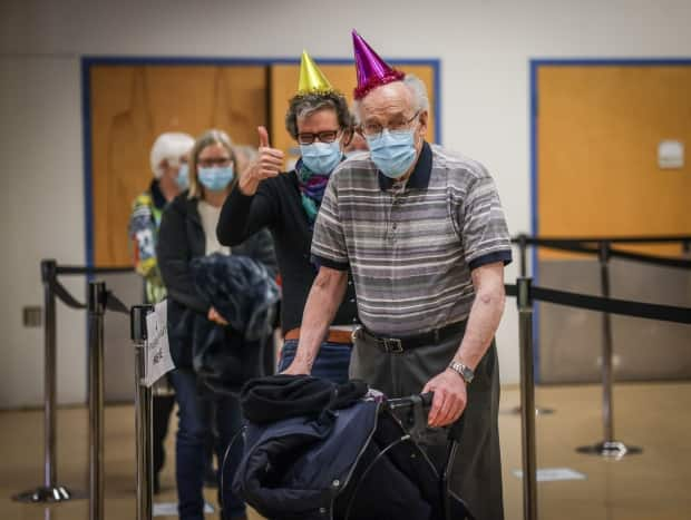 Albertan Karl Kuhnlein, 90, and family wore party hats to celebrate Kuhnlein's COVID-19 vaccination on Feb. 24, 2021. Kuhnlein told Alberta Health Services staff he was looking forward to playing pool with friends again and seeing his grandchildren. (Alberta Health Services - image credit)