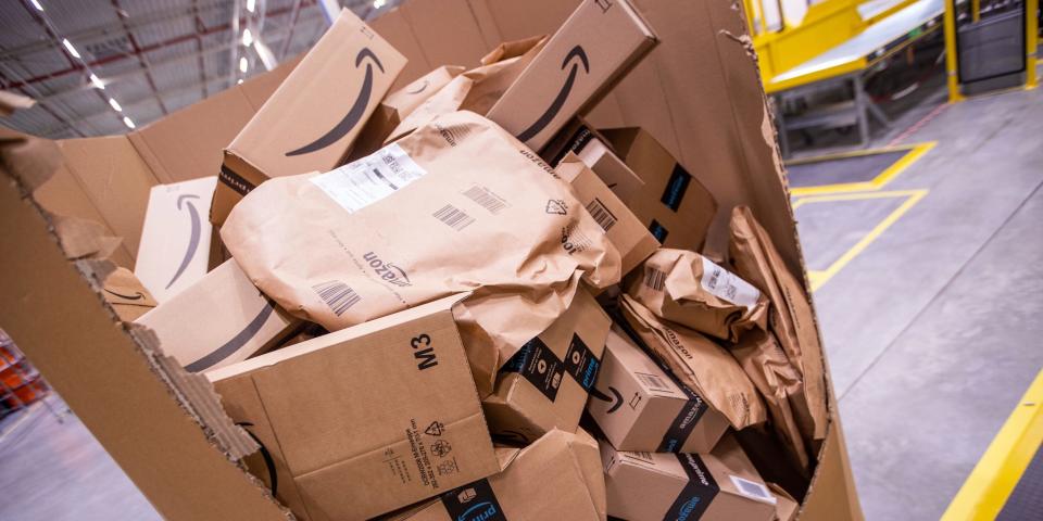 An extra large cardboard box is cut open to reveal dozens of packages with Amazon branding