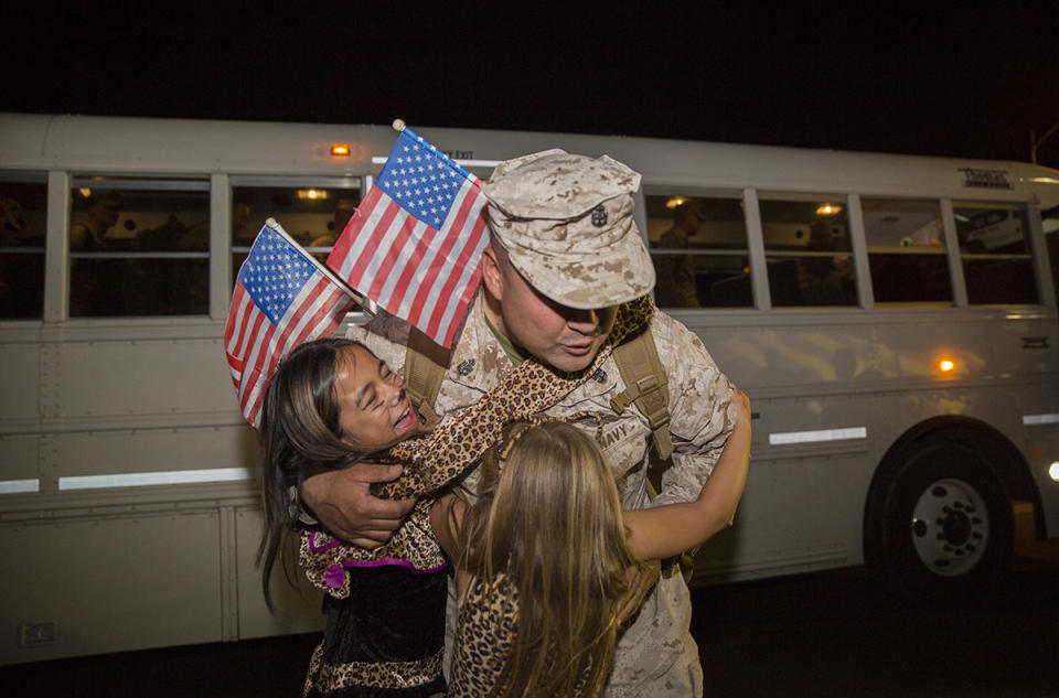 Chief Petty Officer Curtis A. Harmon, leading petty officer, regimental aid station, 7th Marine Regiment, hugs his daughters, Jayleme Harmon, 12, and Anya Harmon, 6, during the regiment's homecoming at Lance Cpl. Torrey L. Gray Field on Oct. 23, 2015.