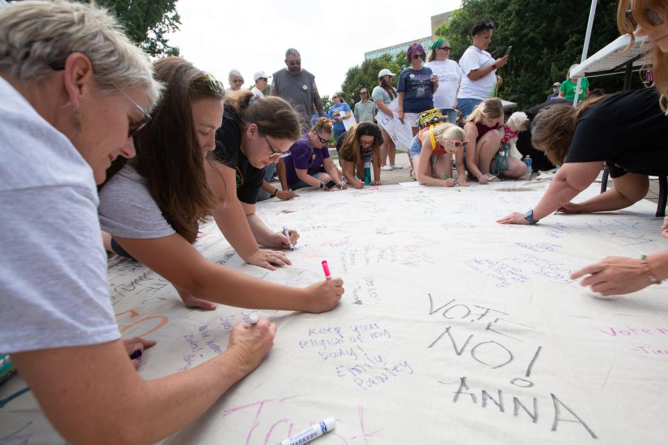 Personal notes and messages are written on a massive piece of canvas during an abortion-rights rally Saturday at the Kansas Statehouse.