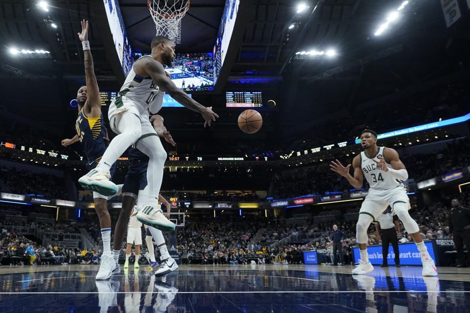Milwaukee Bucks' Damian Lillard (0) makes a pass to Giannis Antetokounmpo (34) while being defended by Indiana Pacers' Bruce Brown (11) during the second half of an NBA basketball game, Wednesday, Jan. 3, 2024, in Indianapolis. (AP Photo/Darron Cummings)