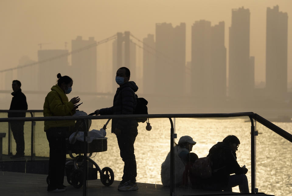 FILE - In this Jan. 15, 2021, file photo, residents enjoy the sunset along the riverbank in Wuhan in central China's Hubei province. Couples go on dates, families dine out at restaurants, shoppers flock to stores. Face masks aside, people are going about their daily life pretty much as before in the Chinese city that was first hit by the COVID-19 pandemic. (AP Photo/Ng Han Guan, File)