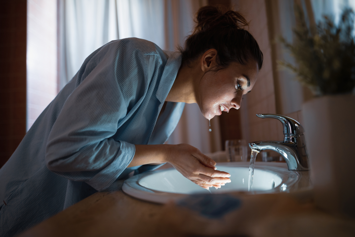 Woman Cleaning Her Face With Water in the Bathroom