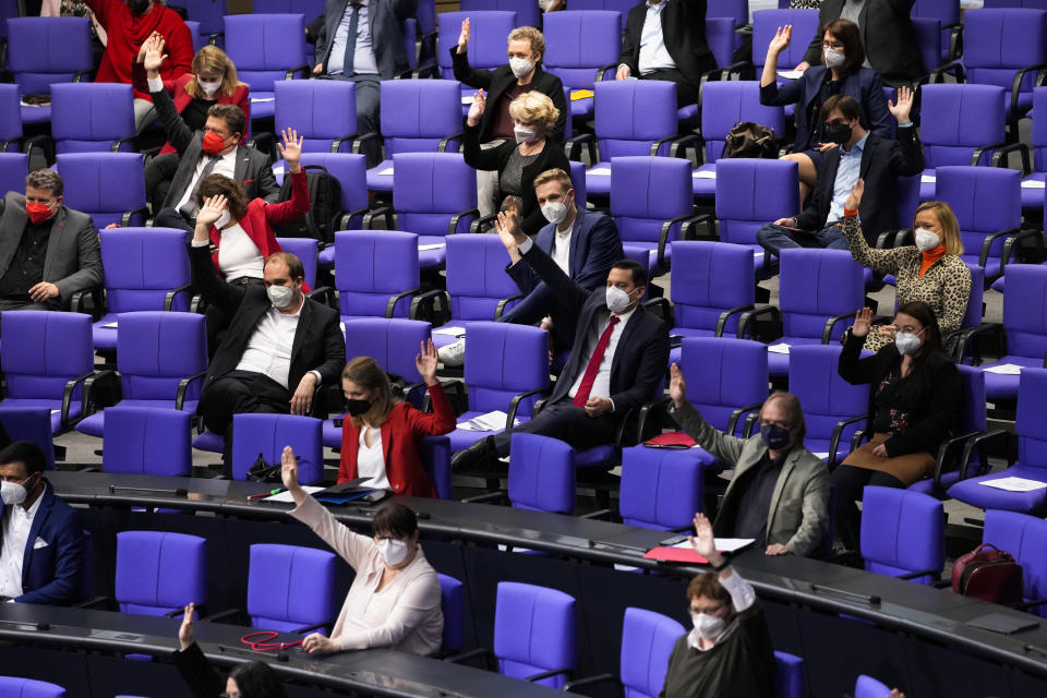 Lawmakers vote the tightening of the rules in the parliament building to combat the coronavirus during a session of the Parliament Bundestag in Berlin, Germany, Wednesday, Jan. 12, 2022. (AP Photo/Markus Schreiber)