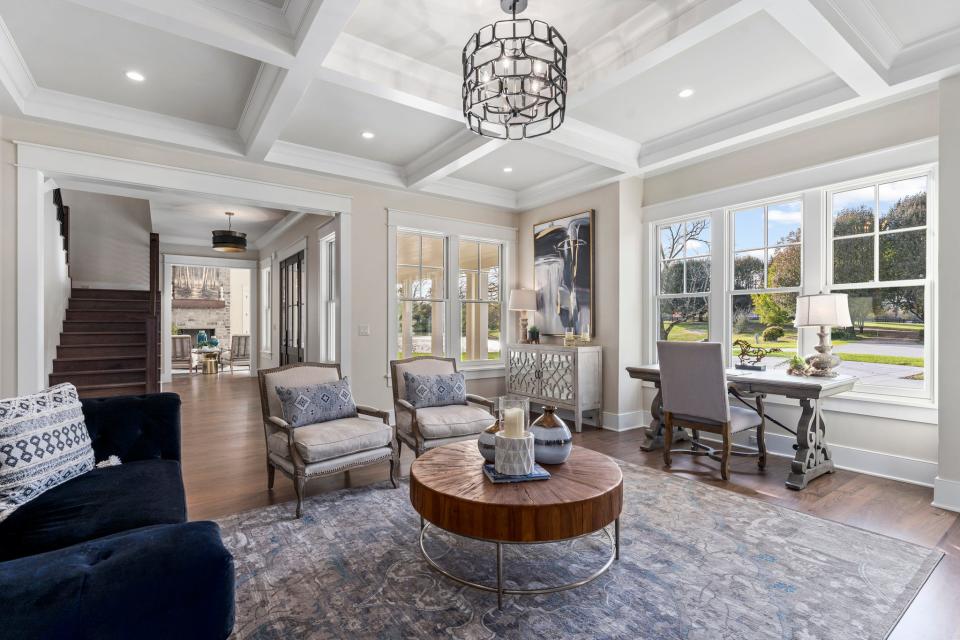 This view of the living room shows the large windows and open foyer that leads into the den.