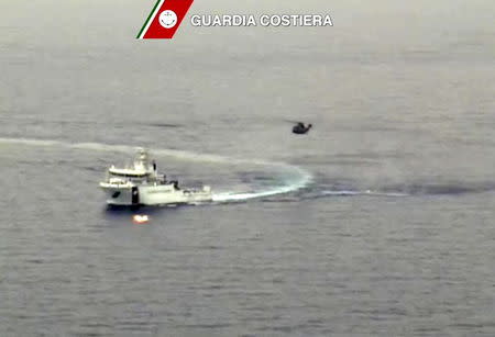 An Italian coast guard vessel is seen with an helicopter during the search and rescue operation underway after a boat carrying migrants capsized overnight, with up to 700 feared dead, in this still image taken from video April 19, 2015. As many as 700 people were feared dead after the fishing boat packed with migrants capsized off the Libyan coast overnight, in what may be one of the worst disasters of the Mediterranean migrant crisis, officials said on Sunday. Twenty-eight people were rescued and 24 bodies recovered from the 20 metre-long vessel, which sank around 70 miles from the Libyan coast, south of the southern Italian island of Lampedusa, the Italian coast guard said. REUTERS/Guardia Costiera/Handout via Reuters TV