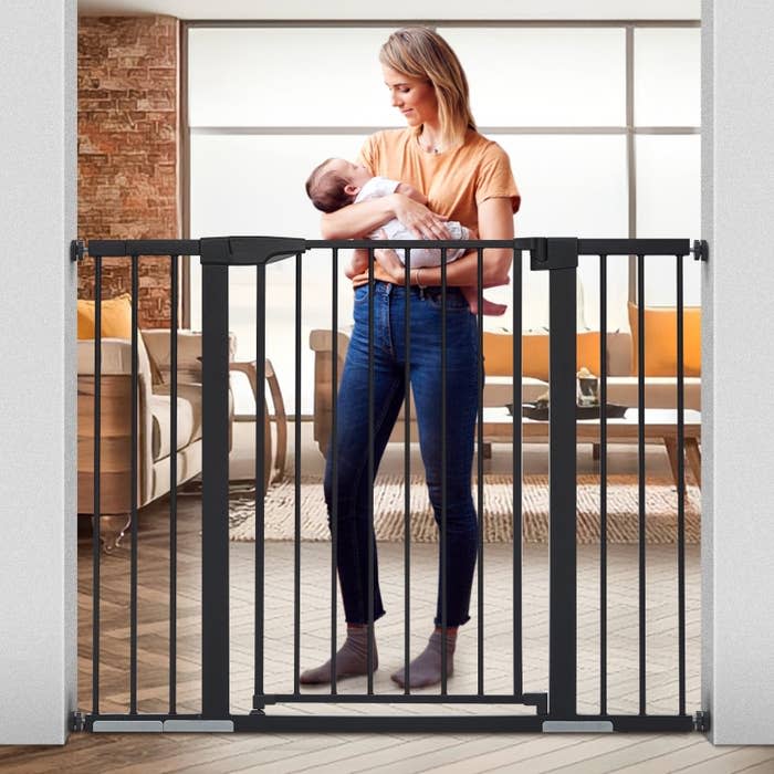 Model holds baby behind a baby gate