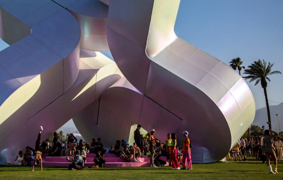 Festivalgoers take shade beneath 'Holoflux' by Guvenc Ozel during the Coachella Valley Music and Arts Festival at the Empire Polo Club in Indio, Calif., Friday, April 14, 2023.