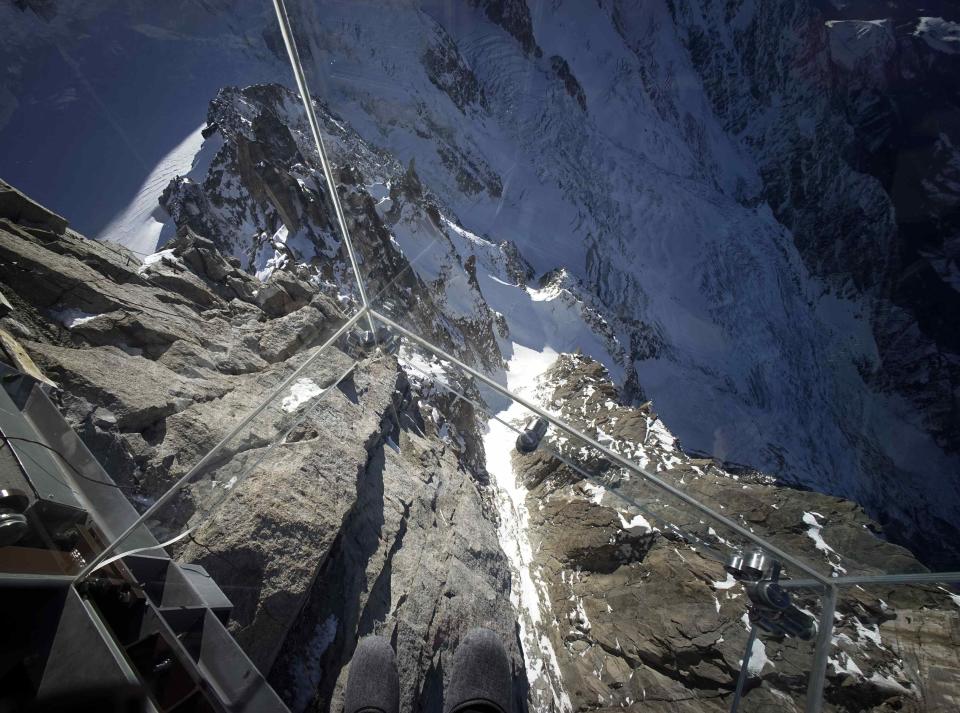 View looking downwards from the 'Step into the Void' installation during a press visit at the Aiguille du Midi mountain peak above Chamonix, in the French Alps, December 17, 2013. The Chamonix Skywalk is a five-sided glass structure installed on the top terrace of the Aiguille du Midi (3842m), with a 1,000 metre drop below, where visitors can step out from the terrace, giving the visitors the impression of standing in the void. The glass room will open to the public on December 21, 2013. REUTERS/Robert Pratta (FRANCE - Tags: SOCIETY TRAVEL CITYSCAPE)