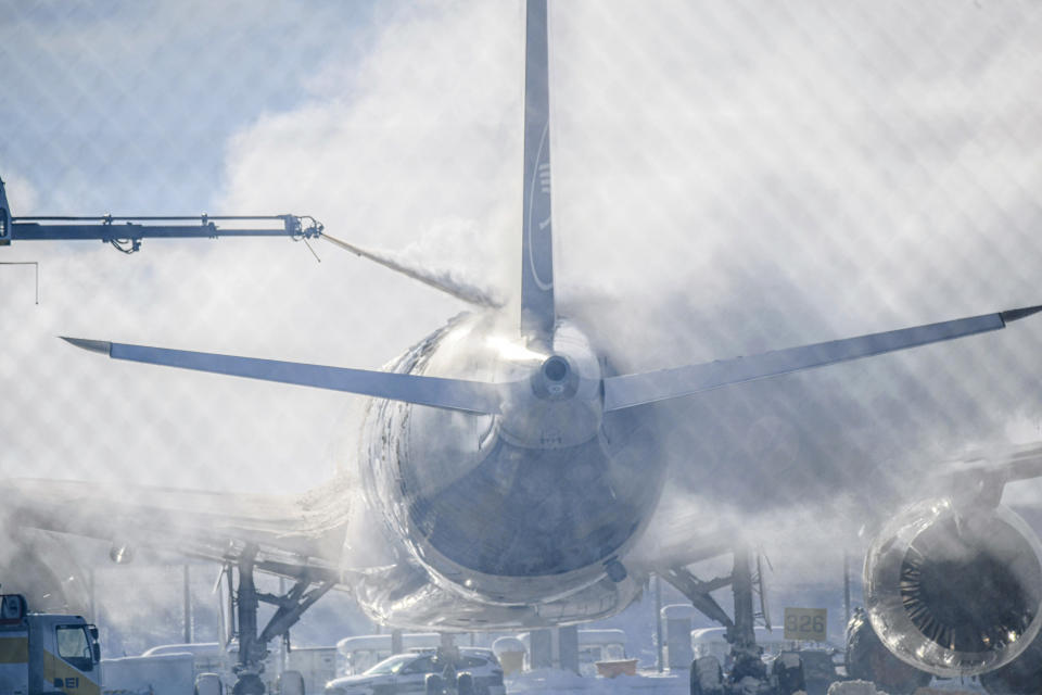 A passenger plane is cleared of ice in Munich Airport, Germany, Tuesday Dec. 5, 2023. After an interruption of several hours due to the weather conditions, Munich Airport has resumed operations. (Jason Tschepljakow/dpa via AP)