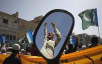 A supporter of the Pakistani religious political party Jamaat-e-Islami is reflected in a mirror of a motorbike during an anti American and NATO demonstration in Karachi March 23, 2012. About 400 protesters gathered to take part in a protest against the possible re-opening of supply routes through Pakistan to NATO troops in Afghanistan, which have been closed since a cross-border attack by NATO forces in Afghanistan that killed 24 Pakistani soldiers on the Pakistan border on November 26, 2011.