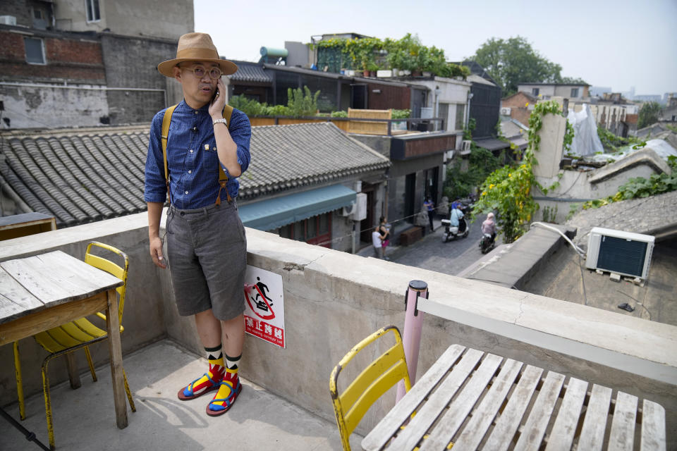 Cafe owner Phil Ma talks on his phone as he stands on the roof of his shop in a neighborhood popular with tourists in central Beijing, Tuesday, Aug. 3, 2021. From the Great Wall to the picturesque Kashmir valley, Asia's tourist destinations are looking to domestic visitors to get them through the COVID-19 pandemic's second year. With international travel heavily restricted, foreign tourists can't enter many countries and locals can't get out. Ma said his cafe has felt the effects of tighter restrictions on travel as China worked to contain outbreaks connected to the Delta variant. (AP Photo/Mark Schiefelbein)