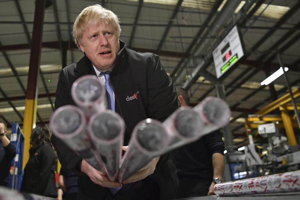 Britain's Prime Minister Boris Johnson, centre, gestures with Christmas wrapping paper, during a visit to IG Design Group, wrapping paper designer and producer in Hengoed, south Wales, Wednesday, Dec. 11, 2019 on the final day of campaigning for the general election. Britain goes to the polls on Dec. 12. (Ben Stansall/Pool Photo via AP)