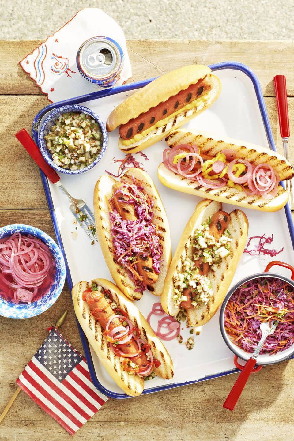 grilled hot dogs with various toppings on a white serving tray