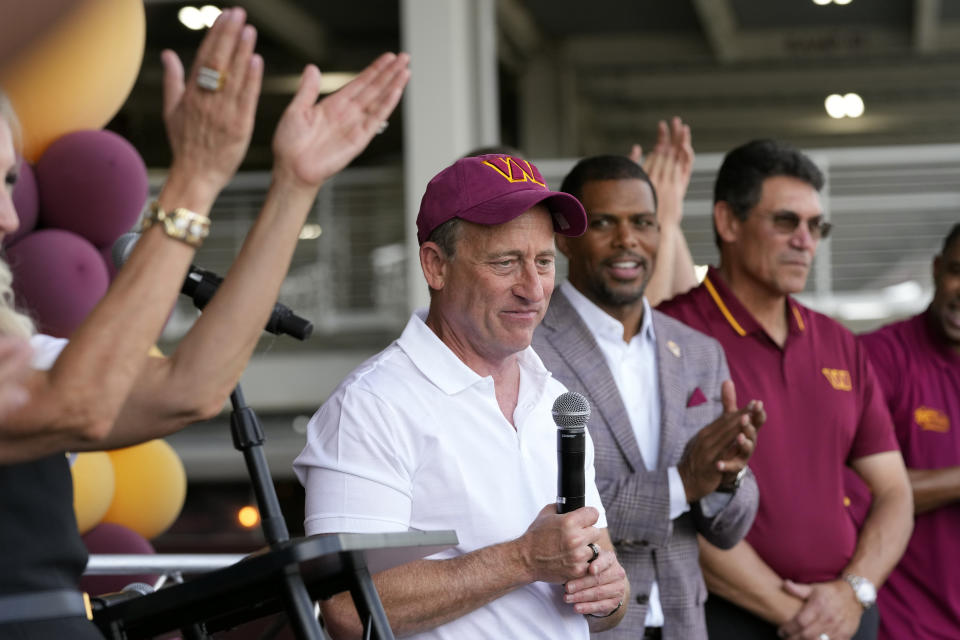 FILE - Josh Harris, center, the leader of a group buying the Washington Commanders, speaks at an NFL football pep rally at FedEx Field in Landover, Md., Friday, July 21, 2023. Standing alongside Harris are team president Jason Wright and head coach Ron Rivera. The Commanders have a new ownership group led by Josh Harris, a new starting quarterback in Sam Howell and a new offensive coordinator in Eric Bieniemy. The buzz has led to their season opener being sold out with home fans expected to make up the vast majority of the crowd.(AP Photo/Alex Brandon, File)