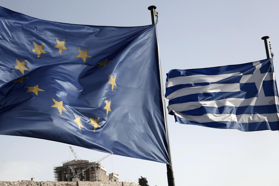 A Greek and a European Union flag billow in the wind as the ruins of the fifth century BC Parthenon temple is seen in the background on the Acropolis hill, in Athens, Friday, Jan. 23, 2015. (AP Photo/Petros Giannakouris)