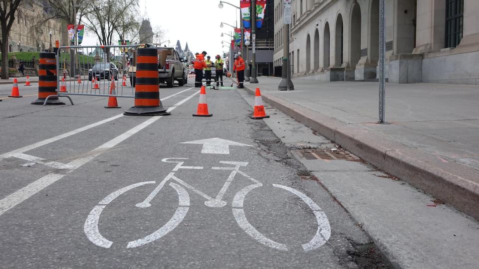 Default Caption Workers paint a bike lane on Wellington Street in downtown Ottawa April 27, 2023, the day before this part of the road reopens to public vehicles.