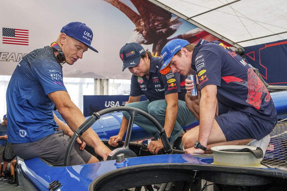 In this photo provided by SailGP, Jimmy Spithill, left, CEO & driver of USA SailGP Team, shows the cockpit and wheel of their F50 catamaran to Max Verstappen, right, and Sergio Perez, Red Bull Racing Formula One drivers, prior to them both joining the USA SailGP Team as sixth sailors for a 'drag race' against Australia SailGP Team ahead of the France Sail Grand Prix in St. Tropez, France on Sept. 6, 2022. Two of the world's best skippers are trying to reclaim their sea legs before falling further behind in SailGP's race for the $1 million Season 3 championship. (Adam Warner/SailGP via AP)