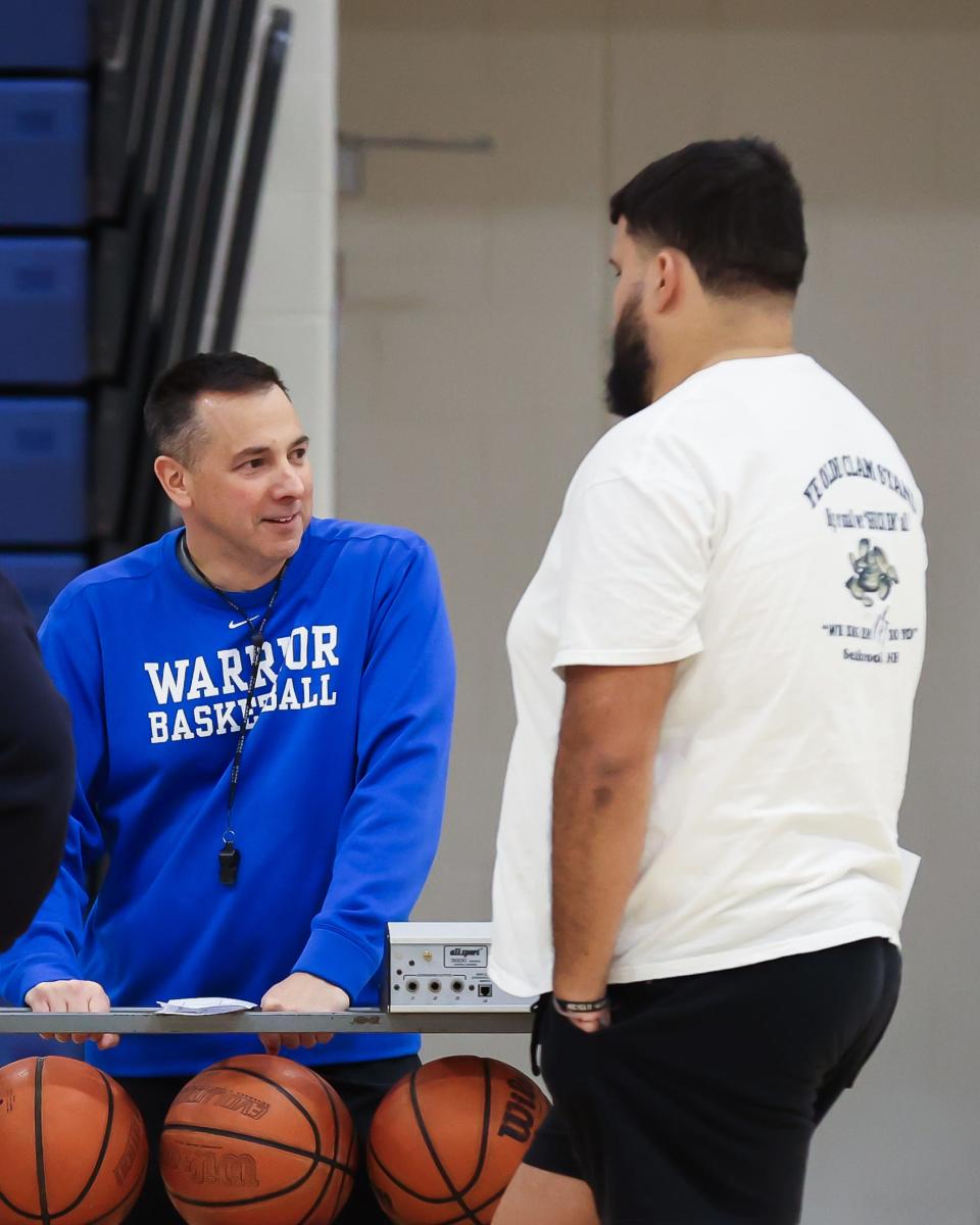 Winnacunnet High School boys basketball coach Jay McKenna, left, talks with former player and now assistant coach Seth Provencher during a break in practice Tuesday at the high school.