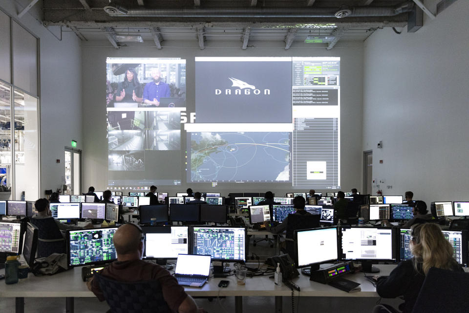 In this Thursday, March 19, 2020 photo made available by SpaceX, SpaceX teams in Firing Room 4 at NASA's Kennedy Space Center in Cape Canaveral, Fla., work with the company's Mission Control in Hawthorne, Calif., along with NASA flight controllers in Mission Control Houston, on a full simulation of launch and docking of the Crew Dragon spacecraft, with NASA astronauts Bob Behnken and Doug Hurley participating in SpaceX's flight simulator. (SpaceX via AP)