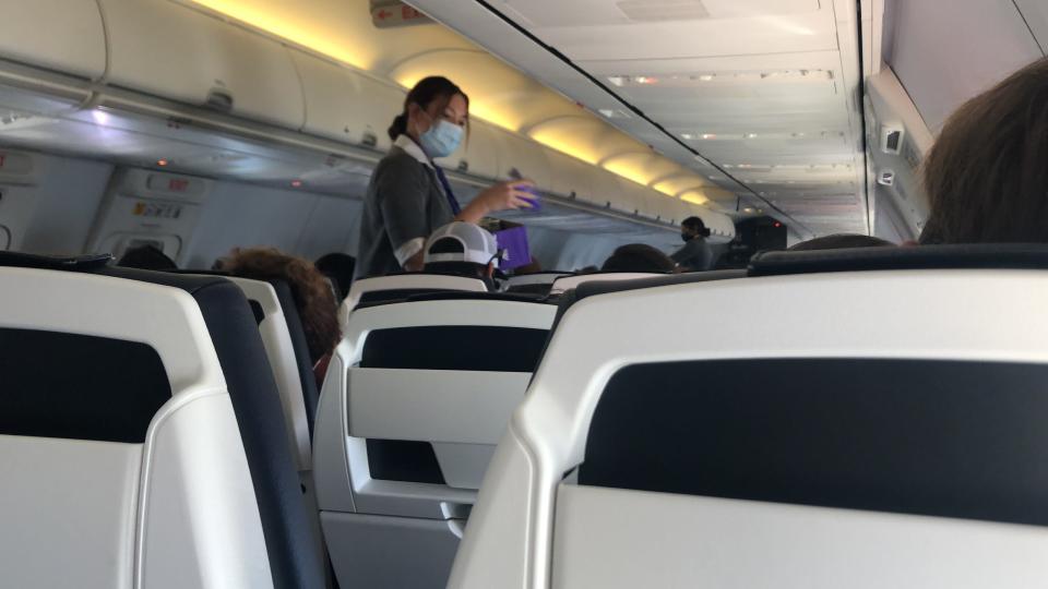 An Avelo flight attendant hands out a snack pack on a flight. The new airline serves a small bottle of water and Lorna Doone cookies.