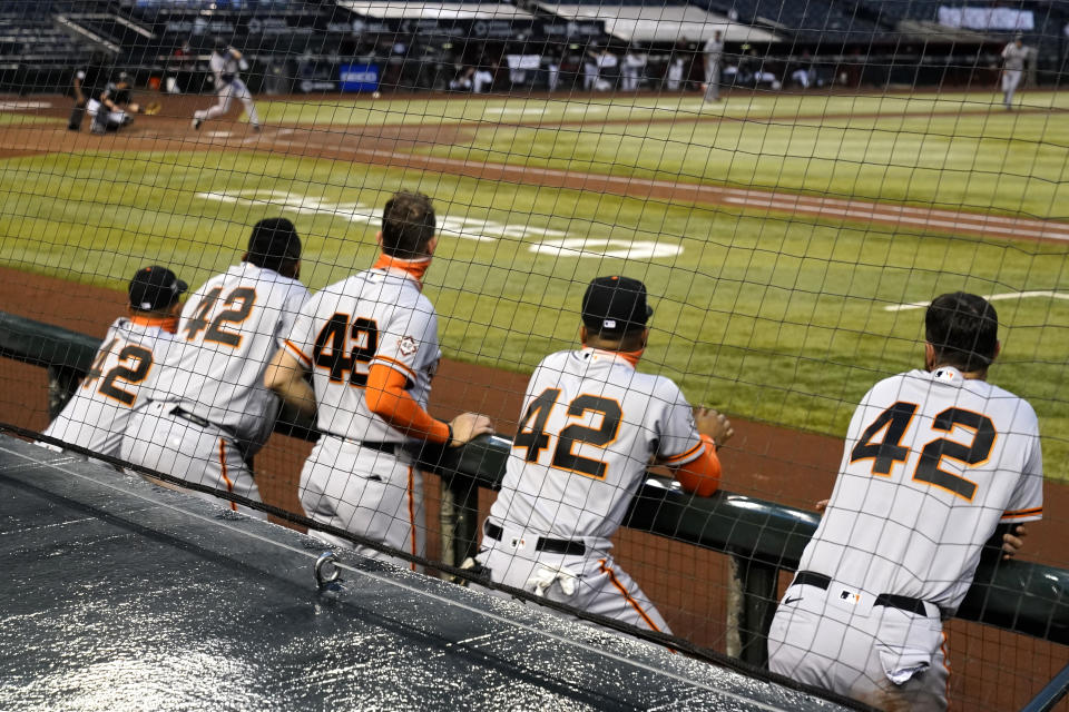 San Francisco Giants players watch from the dugout in the fifth inning during a baseball game against the Arizona Diamondbacks, Saturday, Aug 29, 2020, in Phoenix. Players from both teams wore No. 42 on their jerseys in honor of baseball great Jackie Robinson. (AP Photo/Rick Scuteri)