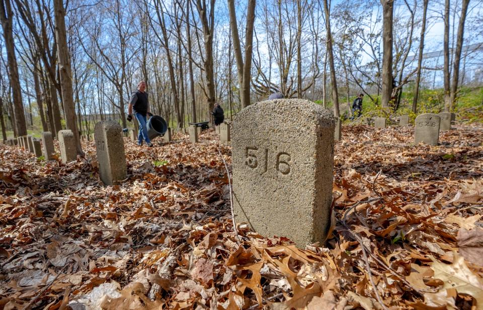 Volunteers clear debris from the State Farm Cemetery Annex grounds in Cranston on Saturday. The 1,049 headstones bear only numbers instead of the names of the poor and often mentally ill people buried there from 1875 through the early 1900s.