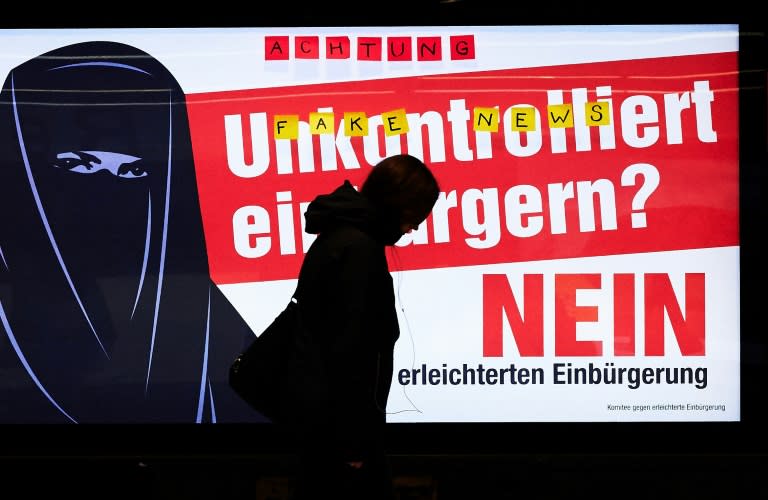 A man walks past an electoral poster by the Committee against Facilitated Naturalization/Citizenship reading "Uncontrolled Naturalisation? No" featuring a woman wearing a niqab, in a train station in Zurich, on February 7, 2017