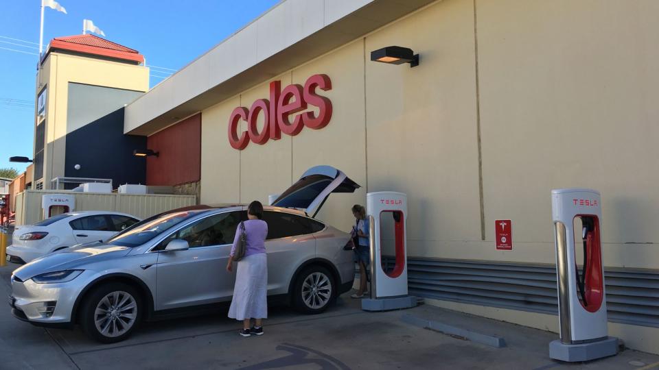 Tesla chargers and Tesla plugged in outside Coles