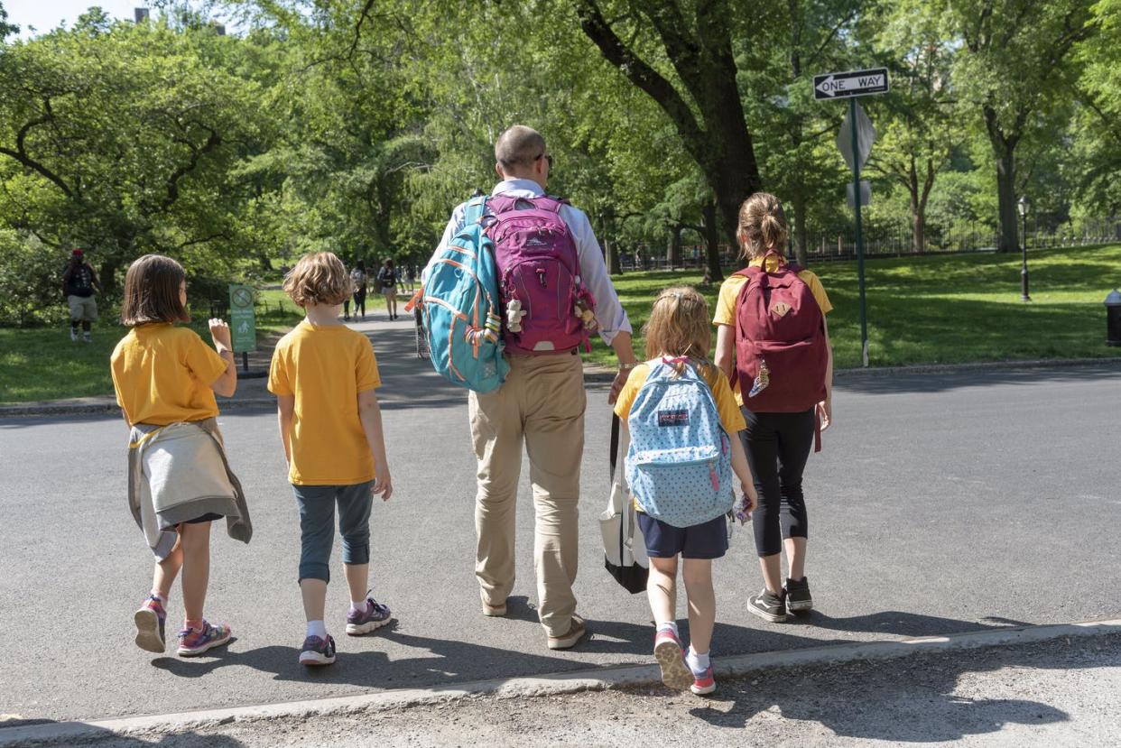 <span class="caption">Raising children strains most household budgets.</span> <span class="attribution"><a class="link " href="https://www.gettyimages.com/detail/news-photo/man-escorting-young-female-students-from-school-to-home-in-news-photo/1084632220" rel="nofollow noopener" target="_blank" data-ylk="slk:Universal Images Group Editorial/Getty Images;elm:context_link;itc:0;sec:content-canvas">Universal Images Group Editorial/Getty Images</a></span>