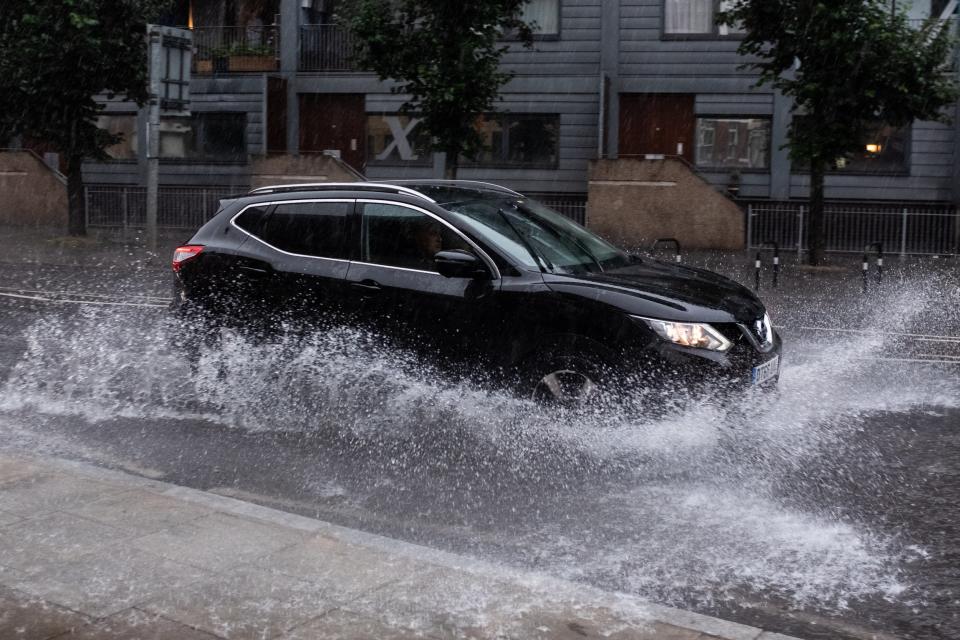 Cars drive through standing water in Stoke Newington, east London (Ian Hinchcliffe/PA) (PA Wire)