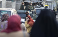 Kashmiri women walk past Indian security officers keeping guard near the site of an attack on the outskirts of Srinagar, Indian controlled Kashmir, Thursday, Nov. 26, 2020. Anti-India rebels in Indian-controlled Kashmir Thursday killed two soldiers in an attack in the disputed region’s main city, the Indian army said.(AP Photo/Mukhtar Khan)