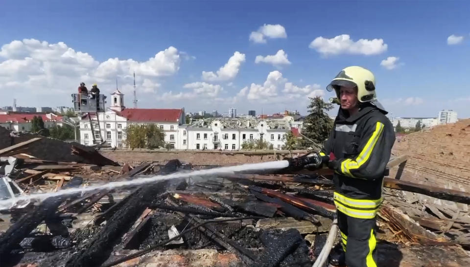 In this photo taken from video provided by the Ukrainian Emergency Service, firefighters work on a roof of the Taras Shevchenko Chernihiv Regional Academic Music and Drama Theatre damaged by Russian attack in Chernihiv, Ukraine, Saturday, Aug. 19, 2023. (Ukrainian Emergency Service via AP)