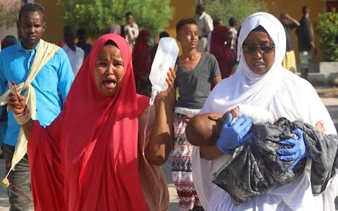 A woman reacts as her injured child is assisted at the Madina hospital following a car bomb explosion at a checkpoint in Mogadishu - Credit: Reuters